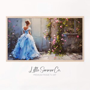 May include: A framed print featuring a woman in a light blue gown, standing before a white door. The artwork has a painterly style, with visible brushstrokes. Pink flowers and green vines adorn the wall. The text "Little Summer Co." is at the bottom.