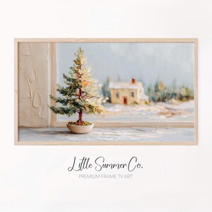 May include: A framed painting of a winter scene. A small, detailed Christmas tree sits on a windowsill, with a snowy landscape and a house in the background. The artwork is signed "Little Summer Co."