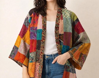 May include: A patchwork kimono-style jacket in a variety of colors, including red, orange, yellow, and blue. The jacket has a loose fit and is made of different fabric squares sewn together. The model is wearing a white tank top and blue jeans.
