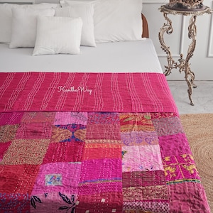 Puede incluir: Un edredón patchwork rosa con una sección superior a rayas y una sección inferior estampada, sobre una cama con almohadas blancas y una colcha blanca. El texto "Kantha Way" es visible en el edredón. La longitud es de unos 200 cm.
