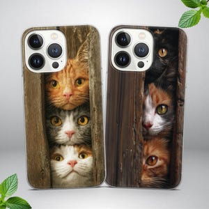 May include: Two phone cases with images of cats peering through wooden planks. One case shows three cats with ginger, grey, and white fur. The other case displays a black cat, a tortoiseshell cat, and a ginger cat.