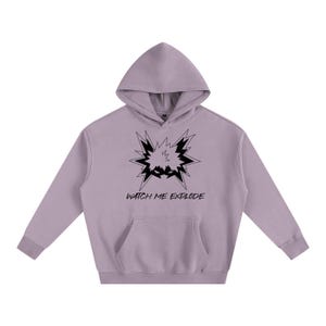 May include: A light purple hoodie with a front pocket and a hood. The hoodie features a black graphic of an explosion with the text "WATCH ME EXPLODE" underneath. The hoodie is made of a soft material.