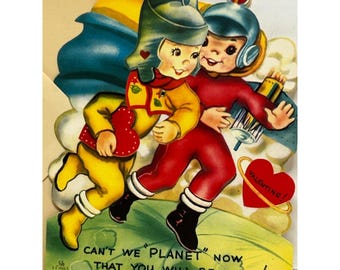 May include: Vintage Valentine's Day card featuring two children in space suits embracing. One child wears a yellow suit and helmet, the other a red suit and helmet. The card includes the text "CAN'T WE PLANET NOW THAT YOU WILL BE MINE!" and a heart with the word "VALENTINE!"
