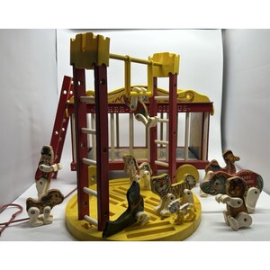 May include: Vintage wooden circus toy set with a red and yellow circus wagon, a ladder, and various animal figures. The set includes a ringmaster, a seal, a tiger, a lion, a bear, and an elephant. The wagon has the text "HER-CII-US."