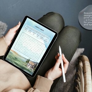 Op de afbeelding: Een tablet met een digitale woordzoeker genaamd Mindful Search en een landschapsillustratie van een huis in een veld. Het scherm bevat een tekstballon met de tekst: Beautifully designed for print or tablet&mdash;a true treat for your mind and eyes.