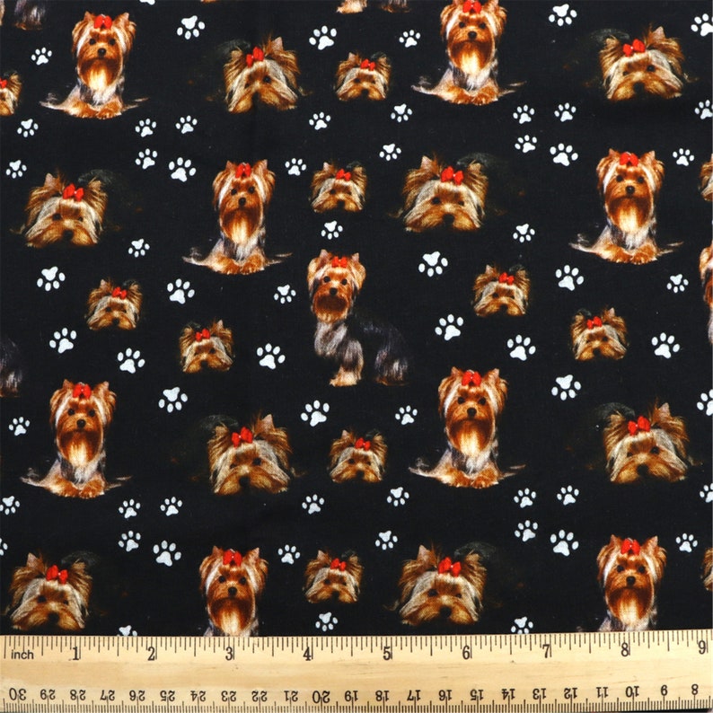 May include: Black fabric with a repeating pattern of Yorkshire Terrier dogs wearing red bows and white paw prints.