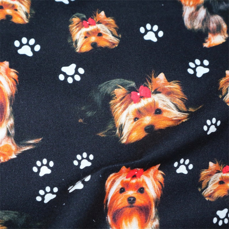 May include: Black fabric with a repeating pattern of Yorkshire Terrier dogs with red bows and white paw prints.