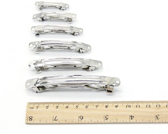 May include: Six silver metal hair clips of varying sizes, lined up from smallest to largest, with a ruler underneath for size reference.