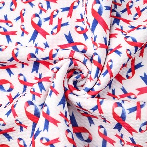May include: White fabric with a repeating pattern of red and blue ribbon designs. The fabric is textured and has a crinkled appearance.