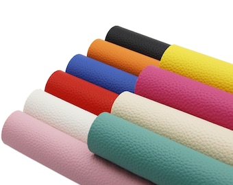 May include: A set of ten faux leather sheets in various colors, including black, orange, yellow, blue, red, white, cream, teal, and pink. The sheets are rolled up and stacked on top of each other.