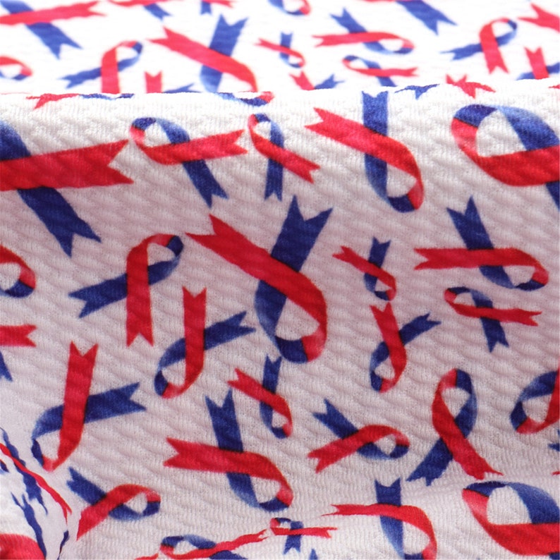 May include: White fabric with a repeating pattern of red and blue ribbon designs. The ribbons are arranged in a diagonal pattern.