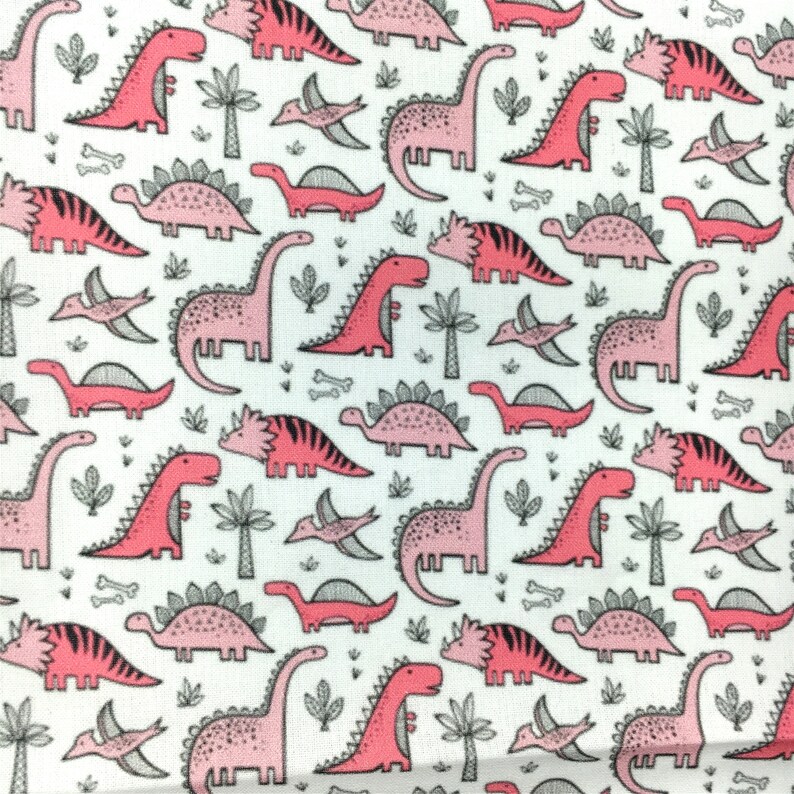 May include: A white fabric with a pink and gray dinosaur pattern. The dinosaurs are in various poses, including walking, running, and standing. There are also small gray bones and leaves scattered throughout the fabric.