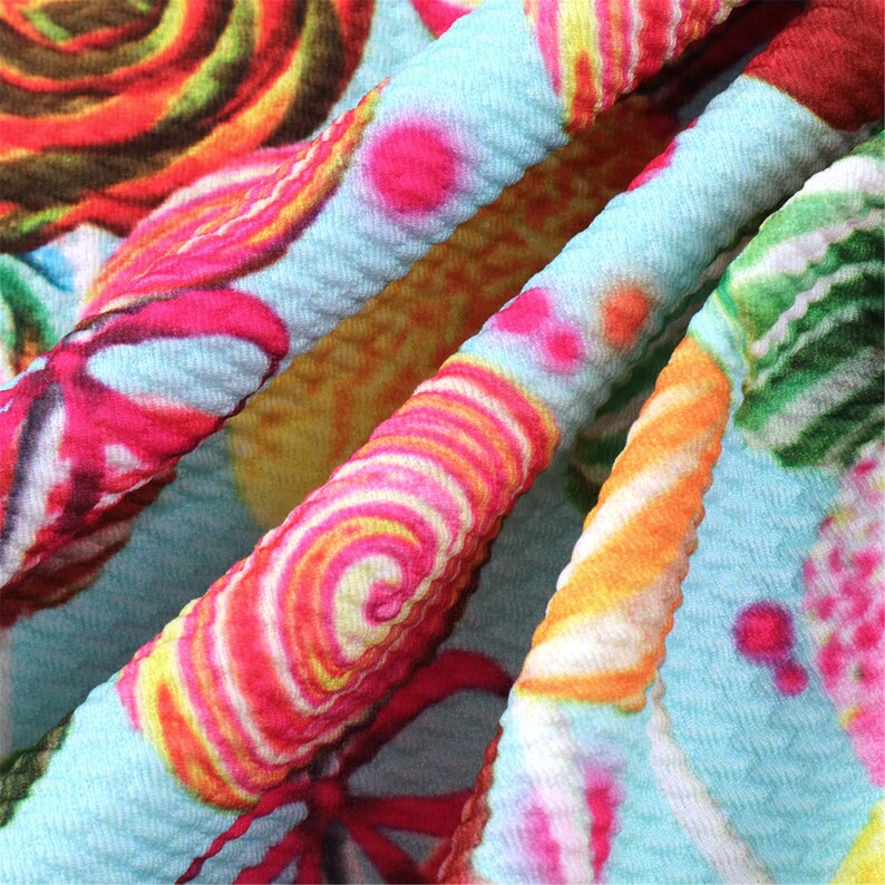May include: A blue fabric with a colorful candy cane and swirl pattern. The fabric has a textured, crinkled look.