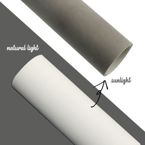 May include: Image showing two rolled paper tubes, one gray and one white, with text indicating "natural light" and "sunlight". The gray tube is at the top, and the white tube is at the bottom, with a diagonal gray line separating them.