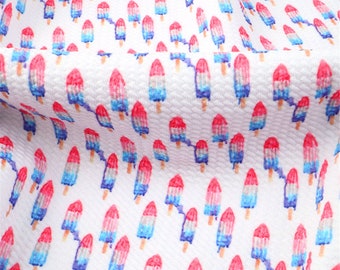May include: White fabric with a repeating pattern of red, white, and blue popsicles.