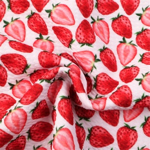 May include: White fabric with a repeating pattern of red strawberries. The strawberries are printed in a realistic style with green leaves.