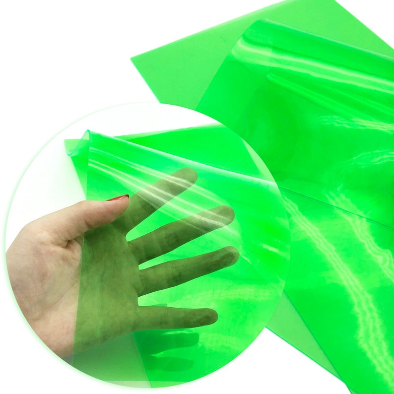 May include: A sheet of bright green translucent vinyl, folded in half and held in a hand. The vinyl is smooth and shiny, and it is clear enough to see through.