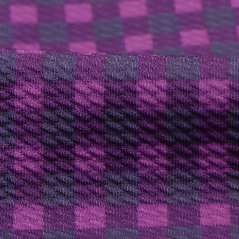 May include: Purple and dark purple checkered fabric with a textured surface.
