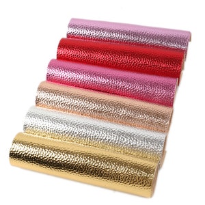 Puede incluir: Un conjunto de seis rollos de piel sint&eacute;tica met&aacute;lica en varios colores, incluyendo oro, plata, rosa y rojo. La piel tiene una superficie texturizada y en relieve.