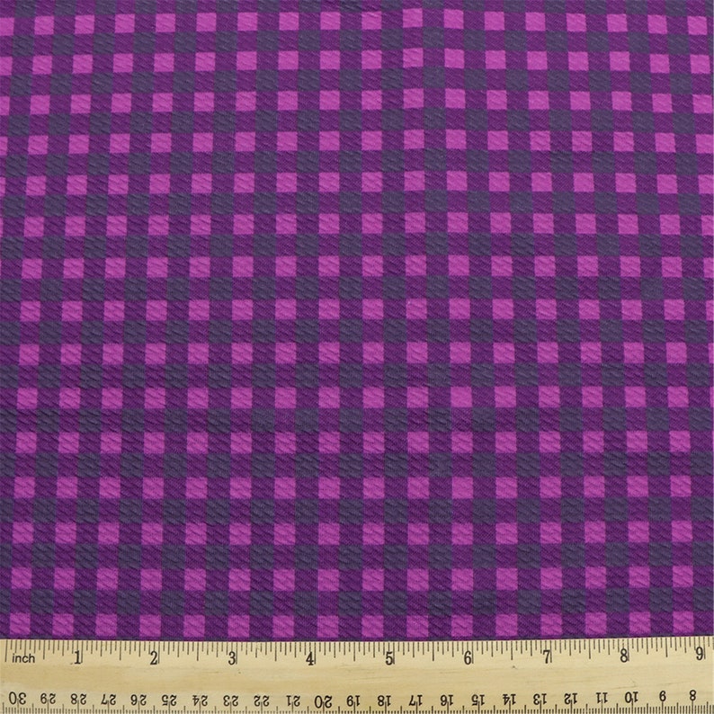 May include: Purple and dark purple checkered fabric with a textured surface.