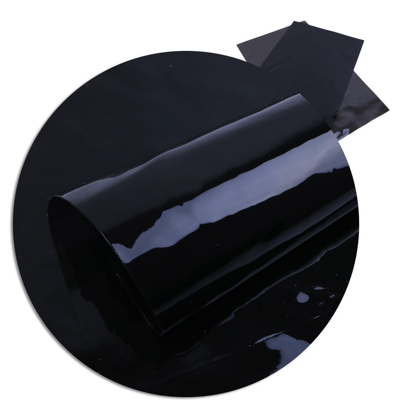May include: A roll of black patent leather fabric. The fabric is shiny and smooth.
