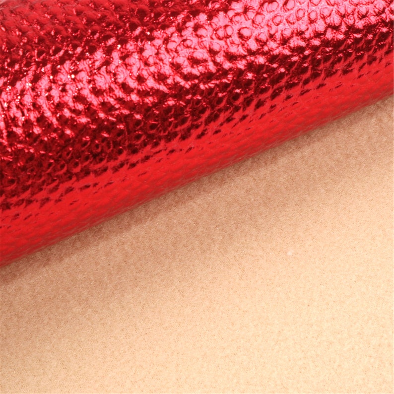 Puede incluir: Un rollo de tela de imitaci&oacute;n de cuero texturizado rojo met&aacute;lico.