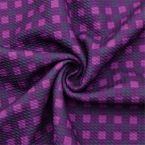 May include: Purple and dark purple checkered fabric with a textured surface.
