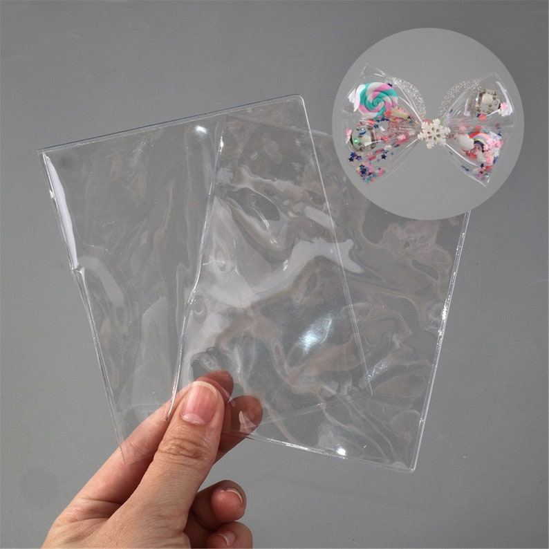 May include: Two clear plastic sleeves for storing and displaying small items, such as jewelry or craft supplies.