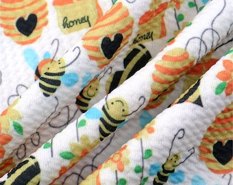 May include: White fabric with a repeating pattern of bees, honeycombs, and the word "honey".