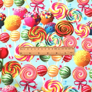 May include: A blue fabric with a repeating pattern of colorful lollipops and cake pops on sticks. The fabric is textured and has a slight sheen.