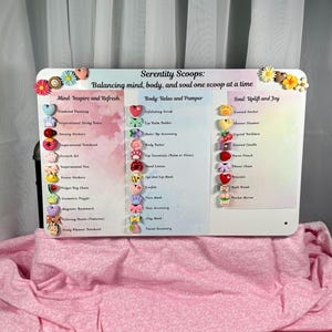 May include: A white rectangular sign with the text "Serenity Scoops" and product categories: Mind, Body, and Soul. The sign is decorated with colorful heart and flower-shaped embellishments. The categories list items like "Diamond Painting" and "Exfoliating Scrub".