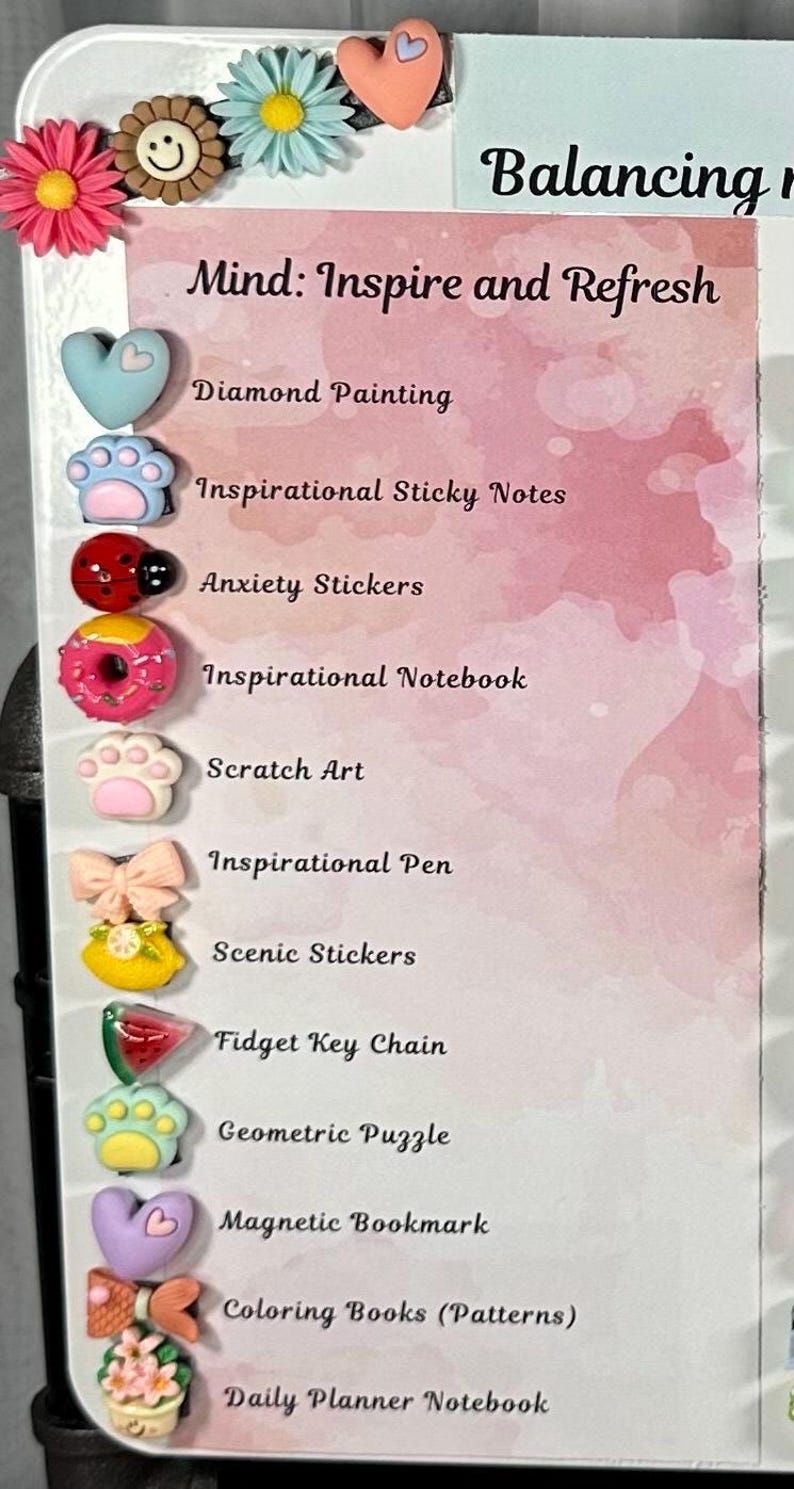 May include: A white board with the text "Balancing" and "Mind: Inspire and Refresh." The board lists various items, including Diamond Painting, Inspirational Sticky Notes, Anxiety Stickers, and a Fidget Key Chain. Decorative flower and heart-shaped embellishments are at the top.