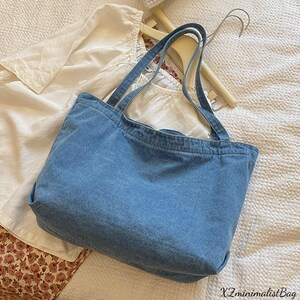 May include: A light blue denim tote bag with two handles. The bag is rectangular and appears to be made of a sturdy denim material. The text "XZminimalistBag" is visible in the bottom right corner.
