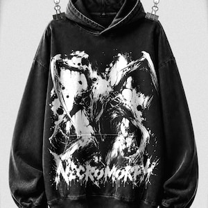 May include: A black hooded sweatshirt featuring a large, white, distressed graphic print of a creature with sharp limbs on the front. The word NECROMORPH is printed in a jagged, stylized font at the bottom of the graphic. The fabric has a faded, washed-out appearance.