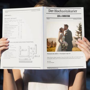 May include: A person holds open a newspaper titled "Der Hochzeitskurier" with the names "LEA & CHRISTIAN" at the top. The newspaper features a wedding photo and a crossword puzzle.