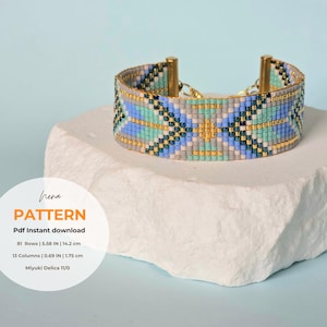 Op de afbeelding: Een kralenarmband met een geometrisch patroon in blauw, teal, grijs, goud en zwart. De armband is 14,2 cm breed en heeft goudkleurige metalen accenten. De afbeelding bevat de tekst "PATTERN".