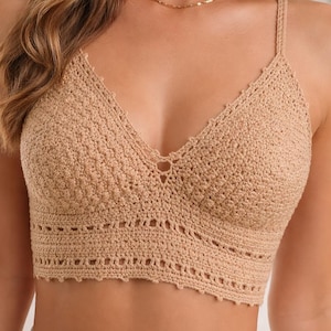 May include: A beige crochet crop top with a V-neck and thin straps. The top has a scalloped edge and a textured pattern. This handmade top is suitable for warm weather and casual wear.