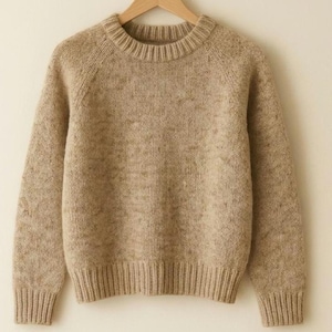 May include: A beige, handmade sweater with a crew neck and ribbed cuffs and hem. The sweater is hanging on a wooden hanger. The word "HANDMADE" is printed in capital letters at the bottom of the image.