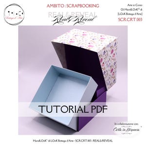 Può includere: Una scatola quadrata aperta con un coperchio a fantasia floreale e una base viola. L'interno della scatola è azzurro. Il testo "TUTORIAL PDF" è visualizzato sulla parte anteriore della scatola. La scatola è per lo scrapbooking.