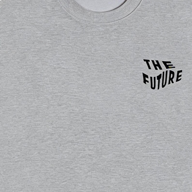 Puede incluir: Una camiseta gris jaspeado con cuello redondo y la frase "THE FUTURE" impresa en negro. El texto est&aacute; ligeramente inclinado y tiene una fuente moderna. La camiseta es de un material suave.
