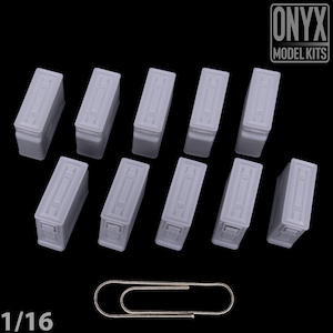 May include: A collection of ten small, light gray rectangular model boxes with detailed lids, arranged on a black surface. A silver paperclip is at the bottom. The text "ONYX MODEL KITS" is in the upper right corner.