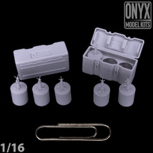 May include: A gray model kit featuring two storage boxes, several cylindrical objects, and a paperclip. The boxes are rectangular with hinged lids. The cylindrical objects have a detailed top. The text "ONYX MODEL KITS" is visible.