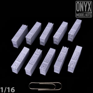 May include: Ten light grey rectangular model kits with detailed features, arranged diagonally on a black background. A silver paperclip is at the bottom. The text "ONYX MODEL KITS" is in the upper right corner. The scale is 1/16.
