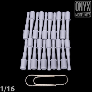 May include: A selection of small, pale grey model kit components, likely for a miniature project. The parts have a cylindrical form with a flared base and a slender, elongated stem. A silver paperclip is included for scale. The text "ONYX MODEL KITS" is visible.
