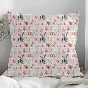 May include: A decorative pillow with a repeating pattern of watercolor goats, strawberries, and floral accents on a pink and white gingham background. The pillow is rectangular and appears to be made of fabric.