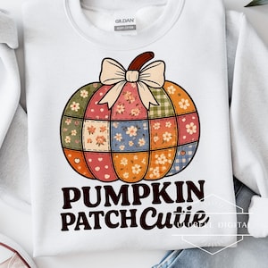 May include: White sweatshirt featuring a colorful patchwork pumpkin design with a bow and the text "PUMPKIN PATCH Cutie". The pumpkin is made of various floral and plaid patterns, perfect for fall.