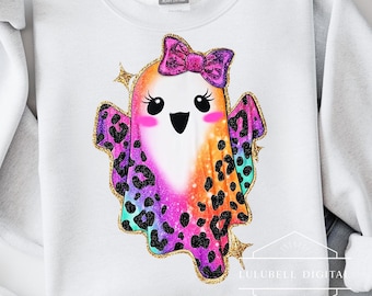 May include: White sweatshirt featuring a colorful ghost design. The ghost has a pink bow, eyelashes, and a leopard print design in purple, orange, and teal. Gold glitter accents the design. The brand name "LULUBELL DIGITAL" is visible.
