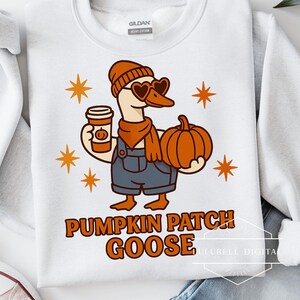 May include: White sweatshirt with a cartoon goose wearing heart-shaped sunglasses, a beanie, and overalls. The goose holds a pumpkin spice latte and a pumpkin. The text "Pumpkin Patch Goose" is printed in orange.