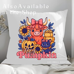 May include: White pillow with a colorful fall-themed design. The design features a cartoon Highland cow, a black cat, a jack-o'-lantern, sunflowers, and the text "Hey Pumpkin". The pillow is decorated with a pink bow.