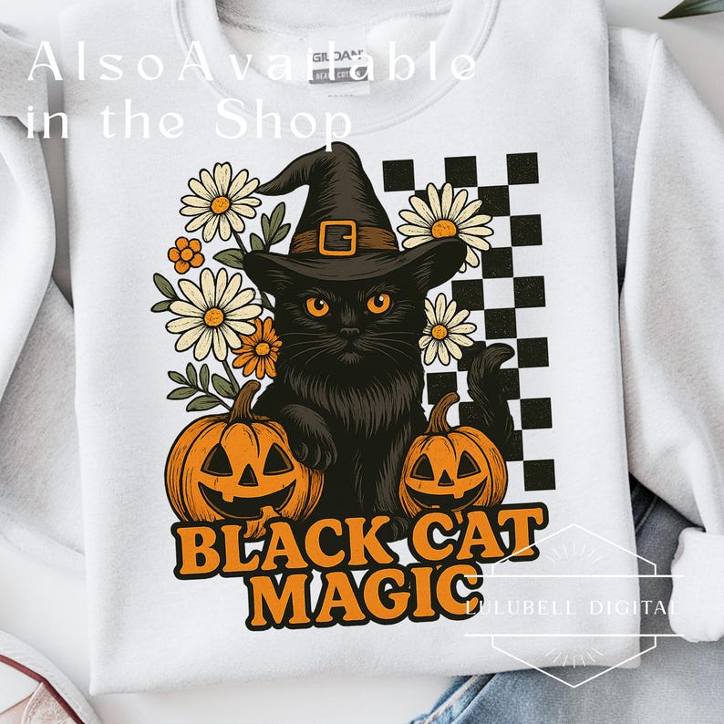 May include: White sweatshirt with a graphic featuring a black cat wearing a witch hat, surrounded by daisies and pumpkins. The text "Black Cat Magic" is displayed in orange. A checkered pattern is on the right side of the design.